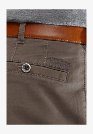 Bruine katoenen broeken hebben een gladde textuur, een metalen knoopsluiting en een bruine leren riem. Een klein 'MEYER'-label is zichtbaar.