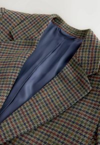 Blazer en laine avec motif pied-de-poule multicolore et doublure intérieure lisse bleu foncé, présenté à plat avec col ouvert et revers.