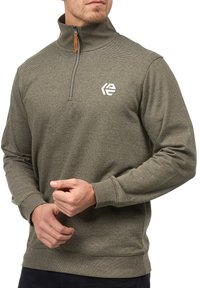 Olivengrøn pullover lavet af tekstureret stof, med en kvart lynlås, ribbede manchetter og et lille hvidt logo på brystet.