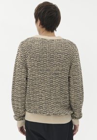 Pleteni pulover v bež in črni barvi z teksturiranim vzorcem. Ima rebraste mansete in rob, okroglo ovratnico ter sproščen kroj.