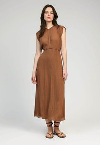 Robe maxi marron à côtes avec de courtes manches à couverture et une taille cintrée, dotée d'un subtil détail de patte. Associée à des sandales plates à lanières.