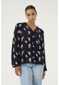 Navy floral blouse in lightweight fabric, featuring pink flowers, green accents, a ruffled neckline, and long sleeves. Paired with light jeans.
