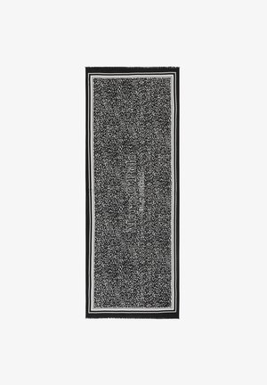 Black and white patterned towel with a fringed edge, featuring the brand name "Marc O'Polo" in bold lettering and a solid border.