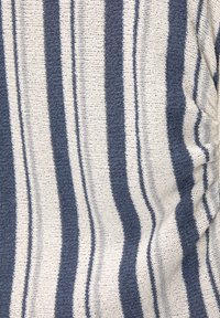 Tissu en tricot avec des rayures alternant bleu marine et blanc. Texture douce avec une trame légèrement lâche. Présente des motifs et des bords irréguliers.