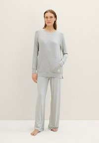 Completo pigiama grigio con una maglietta a maniche lunghe con orlo arrotondato e taschino frontale, abbinato a pantaloni dritti, realizzato in tessuto morbido.