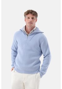 Hellblauer, gerippter Pullover mit kurzem Reißverschluss und breitem Kragen. Weicher Stoff, oversized Passform, mit einem V-förmigen Stitchmuster auf der Brust.