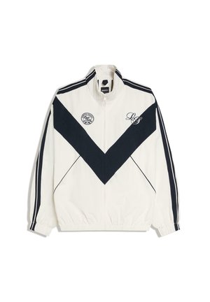 Bela športna jakna na zadrgo s črnim ševronovim vzorcem, črnimi črtami na rokavih, elastičnimi manšetami in logotipi na prsih.