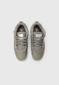 Par de sapatilhas cinzentas e beges com atacadores, solas brancas e logo Jumpman na lingueta e na palmilha, vistas de cima sobre fundo branco.