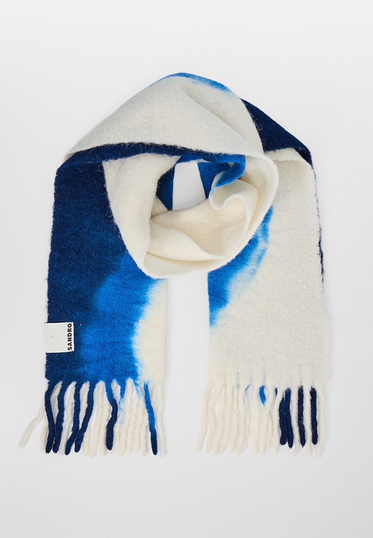 Wollen sjaal met een verloop van blauw naar wit, met rafelige randen en een label met de tekst "SANDRO" aan één uiteinde. Zachte textuur en een gezellige uitstraling.