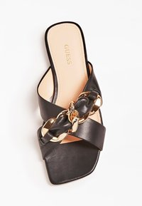 Sandalo scivoloso in pelle nera con un spessore accentuato da una catena d'oro intrecciata, punta quadrata e una soletta beige liscia con il logo del marchio.