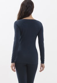 Námořnické tričko s dlouhým rukávem, širokým výstřihem, přiléhavým stylem a hladkým povrchem. Oblečení sahá až k bokům a má úzké rukávy.
