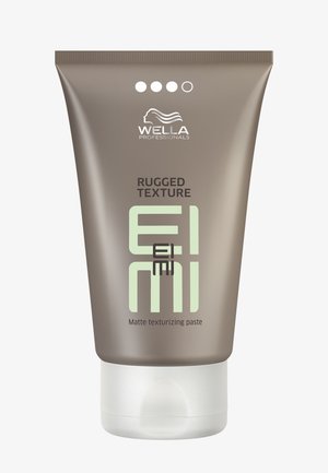 Tube en plastique marron avec un capuchon blanc à rabat, étiqueté "Rugged Texture EIMI" en vert. Contient une pâte texturisante mate.