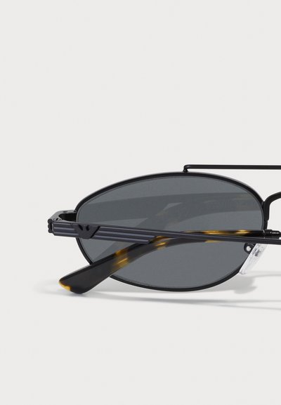 Lunettes de soleil en métal noir avec verres gris, de forme ovale, et branches en écaille de tortue. Possède un design mince et épuré avec des détails subtils.