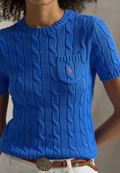 Μπλε κοντομάνικο πουλόβερ με πλεκτό σχέδιο καλώδιο, που διαθέτει στρογγυλή λαιμόκοψη, τσέπη στο στήθος και κεντημένο λογότυπο σε πορτοκαλί χρώμα. Φορεμένο με ζώνη.