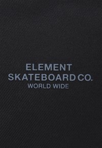 Svart tyg med en strukturerad yta som har texten "ELEMENT SKATEBOARD CO. VÄRLDENS HUVUDSTAD" i ljusgrått, centrerat och i fetstil.