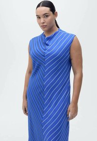 Robe bleue avec des rayures blanches diagonales, design sans manches, encolure asymétrique, texture lisse et silhouette mi-longue.