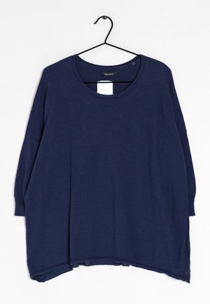 Granatowy, oversize'owy sweter z długim rękawem i okrągłym dekoltem, wiszący na czarnym wieszaku na białym tle.