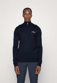 Navy zip-up sweater with long sleeves, featuring a high collar and Callaway logo on the chest. Made from a smooth knit material.