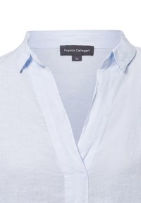 Lichtblauw linnen shirt met een V-hals, korte mouwen en een label met de tekst "Franco Callegari" en maat 36. Gladde textuur.