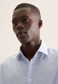 Blauw-wit gestreept shirt met een spread collar en knoopsluiting, gemaakt van een gladde stof met een fijne textuur.