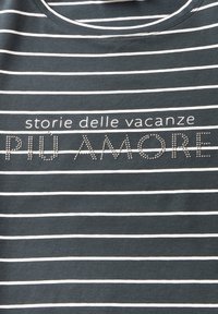 Camiseta de algodón gris oscuro con rayas horizontales blancas. Presenta texto impreso en plata, que dice "storie delle vacanze PIÙ AMORE" en una fuente negrita.