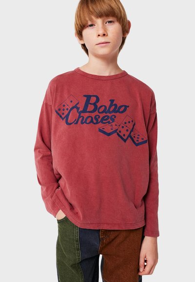 Rotes Langarmhemd mit "Bobo Choses" und Dominospiel-Grafik in Marineblau. Lockerer Schnitt, weicher Stoff, Rundhalsausschnitt und überschnittene Schultern.
