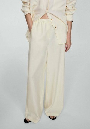 Pantalons larges de couleur crème en tissu léger avec une taille élastique, présentant une coupe décontractée et des poches latérales.