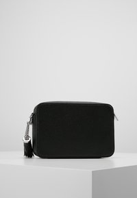 Czarna skórzana torebka crossbody o teksturowanej powierzchni, z srebrnym okuciem, zapięciem na zamek oraz dekoracyjnym paskiem akcentującym. Prostokątny kształt.