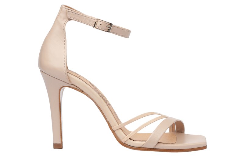 Sandalia de tacón alto de cuero en color nude, con una delgada correa en el tobillo, punta abierta y dos correas delanteras cruzadas. Presenta un tacón afinado y una textura suave.