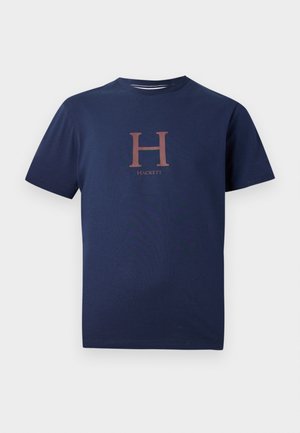 Navy blue cotton t-shirt featuring a large, contrasting copper "H" and the word "Hacket" below in a simple, modern serif font.
