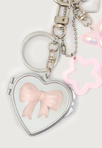 Heart-shaped silver pocket mirror keychain with a pink bow on the cover, attached to a chain with a pink flower-shaped charm.