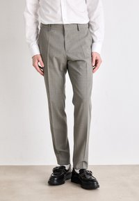 Pantaloni grigi a quadri con una vestibilità su misura, caratterizzati da un davanti piatto, passanti per cintura e tasche laterali, abbinati a scarpe nere.