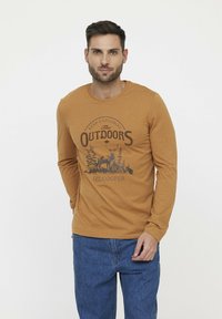 Langarmige bruine t-shirt met een ronde halslijn, voorzien van een grafisch ontwerp van bomen en een hert, met de tekst "The Outdoors" van Lee Cooper.