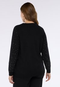 Maglione nero a maniche lunghe con decorazioni borchiate argento su spalle e maniche. Tessuto morbido a maglia, taglio classico.