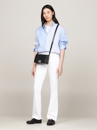 Sort crossbody taske med en metallisk lukning, blå stribet skjorte, hvide flared jeans og sorte lædersko, præsenteret mod en neutral baggrund.
