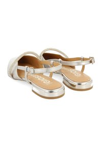 Sandalias plateadas con un brillante hebilla metálica, acentos de rhinestone decorativos y una suela plana y sólida de color marrón claro. Material superior suave.