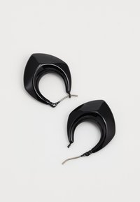 Anneaux en métal noirs avec un design géométrique et angulaire. Fabriqués en matériau brillant, présentant un fermoir à crochet courbé pour un port en toute sécurité.