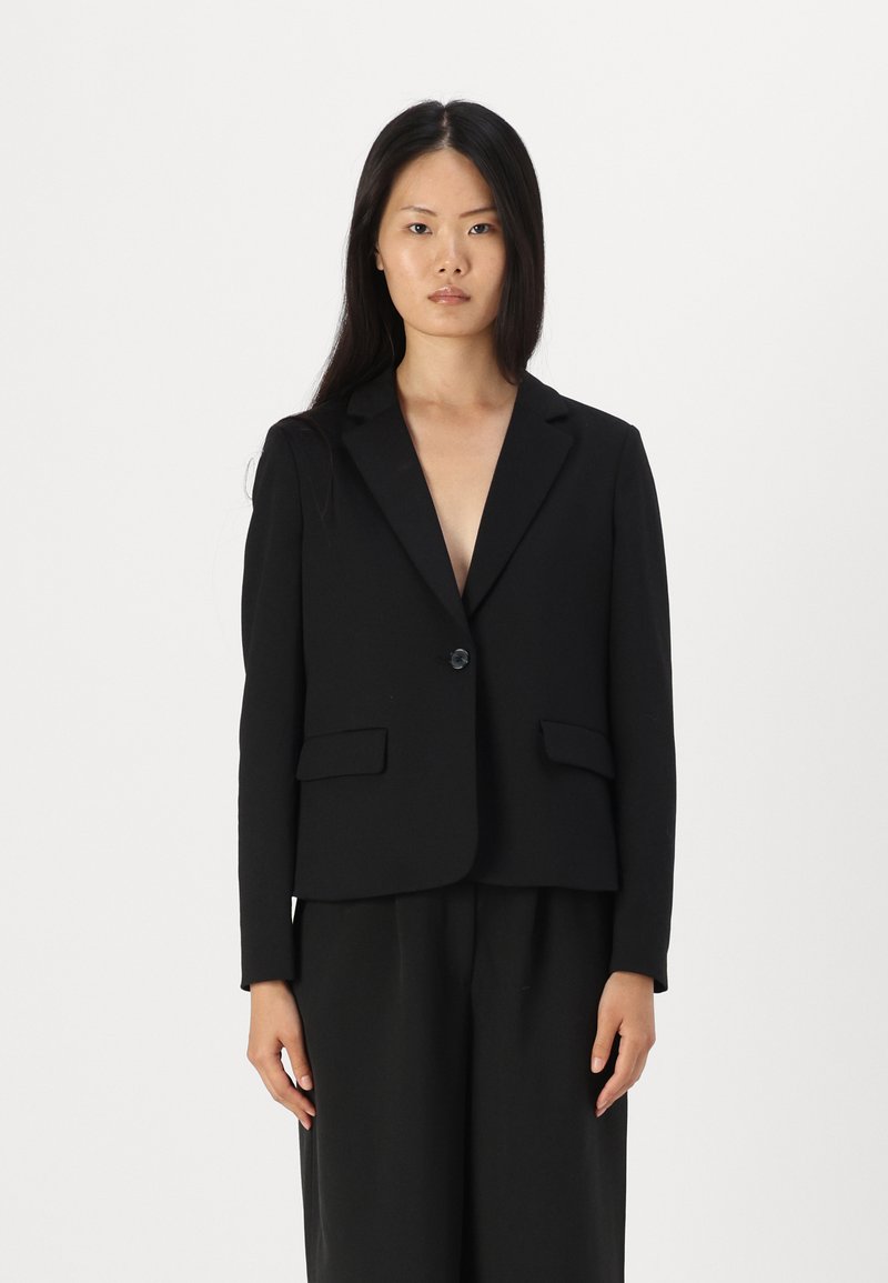 Blazer nero con vestibilità sartoriale, rever a punta, chiusura con un bottone e due tasche frontali, realizzato in tessuto texturizzato.