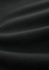 Tissu textile noir mat avec une texture fine, présentant des plis lisses et fluides ainsi qu'une surface uniforme et régulière.
