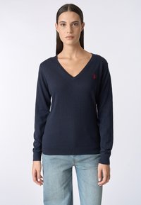 Maglione a V navy in morbido tessuto con maniche lunghe. Presenta un piccolo logo rosso sul lato sinistro del petto e bordi e polsini a coste.