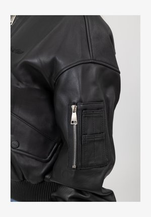 Zwarte leren bomberjack met ribgebreide manchetten, een ritszak op de mouw en een gladde textuur met een subtiele glans.