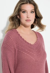 R�óżowy sweter z dzianiny, z falistym dekoltem w kształcie litery V, teksturowanym wzorem i subtelnymi otwartymi oczkami. Miękka tkanina o luźnym kroju.