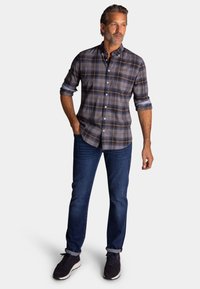 Ruiten overhemd met knopen in marineblauw, beige en grijs; opgerolde mouwen. Draag het met donkerblauwe jeans en zwarte sneakers. Eenvoudig ontwerp, casual pasvorm.