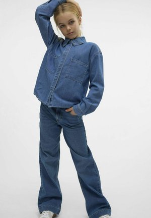 Denimoutfit met een lichtblauwe, lange mouwen shirt met zakken en losse spijkerbroek. De textuur is soepel met een klassieke denim uitstraling.