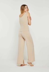 Beiges, geripptes Tanktop und weit geschnittene Hose, mit einem Rundhalsausschnitt, lässiger Passform und Seitenschlitzen an den Hosenbeinen. Weiche Textur.