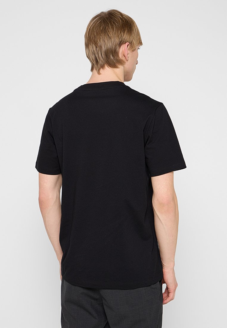 Camiseta de algodón negra de manga corta, con cuello redondo y un diseño liso. La vista trasera muestra hombros sin costuras y un corte relajado.