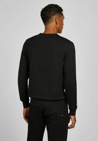 Zwart gebreid sweatshirt met lange mouwen en een ronde hals; geribbelde manchetten en zoom, met een textuurstof voor extra detail.