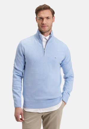 Pull en maille bleu clair avec un col à demi-zip et des ourlets côtelés, superposé à une chemise blanche à col. Texture lisse, design décontracté.