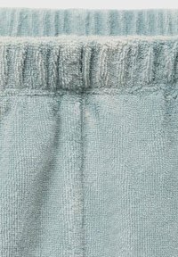 Lichtblauwe badstof shorts met een geribde tailleband, zachte textuur en geplooide details langs de bovenrand.