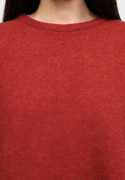 Κόκκινο πλεκτό πουλόβερ με στρογγυλή λαιμόκοψη, με απαλή υφή και ομοιόμορφο χρώμα σε όλο το ύφασμα, κατάλληλο για στρώσεις σε δροσερό καιρό.